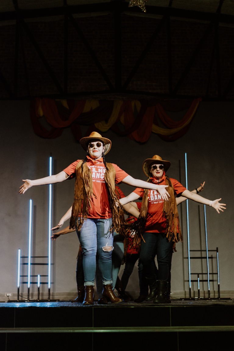 Line dancers performing together on stage in cowboy hats